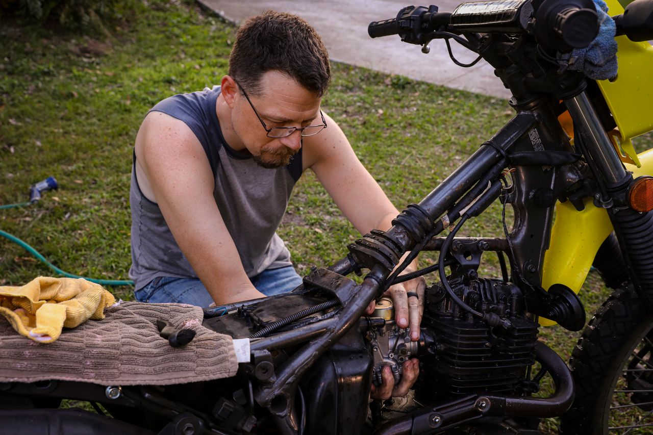 Man performing motorcycle maintenance on a sunny day in Orlando, Florida.