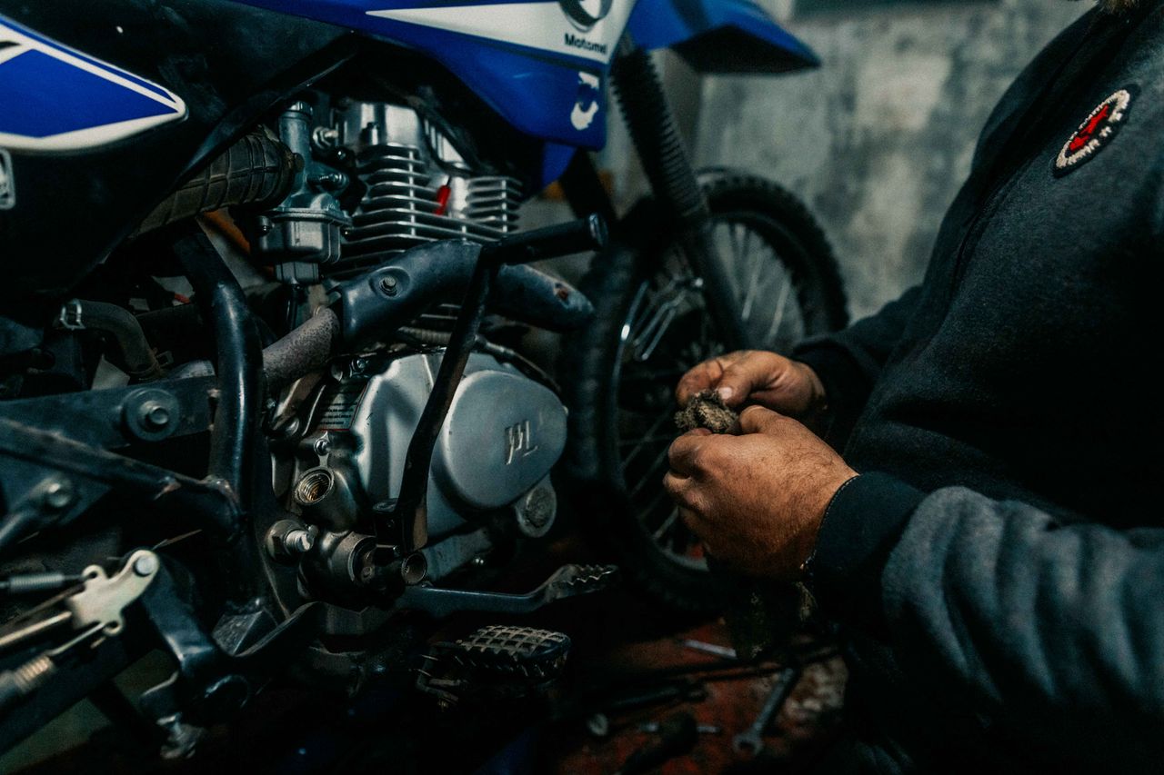 Mechanic works on a motorcycle engine in a garage, focusing on intricate details.
